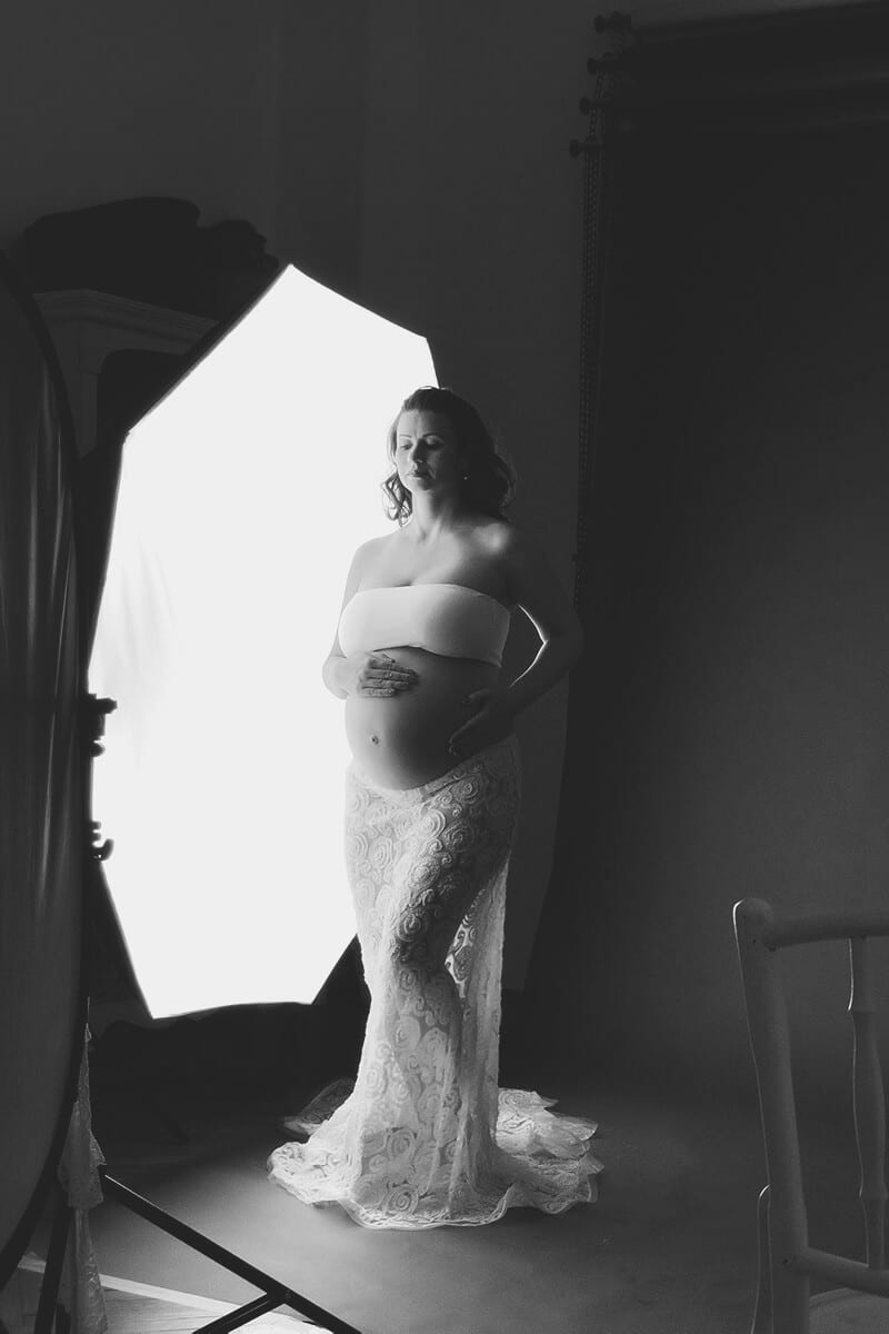 Schwangere Frau in weissen Outfits posiert waehrend eines Workshops fuer Schwangerschaftsfotografie gegen das Licht