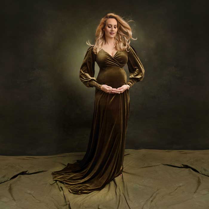 Schwangere-Frau-in-einem-gruenen-Samtkleid-waehrend-eines-Schwangerschaftsfotoshootings