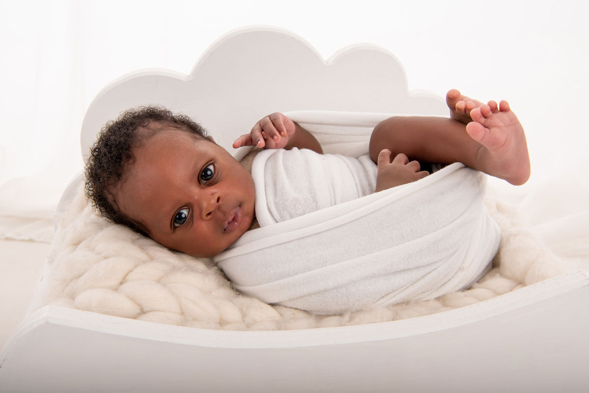 Baby im weissen Bett im Fotostudio
