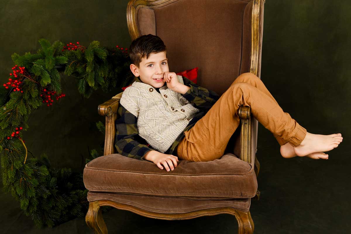 Weihnachts-Fotoshooting-in-Muenchen-ein-Junge-sitzt-auf-einem-Stuhl-in-einem-Fotostudio