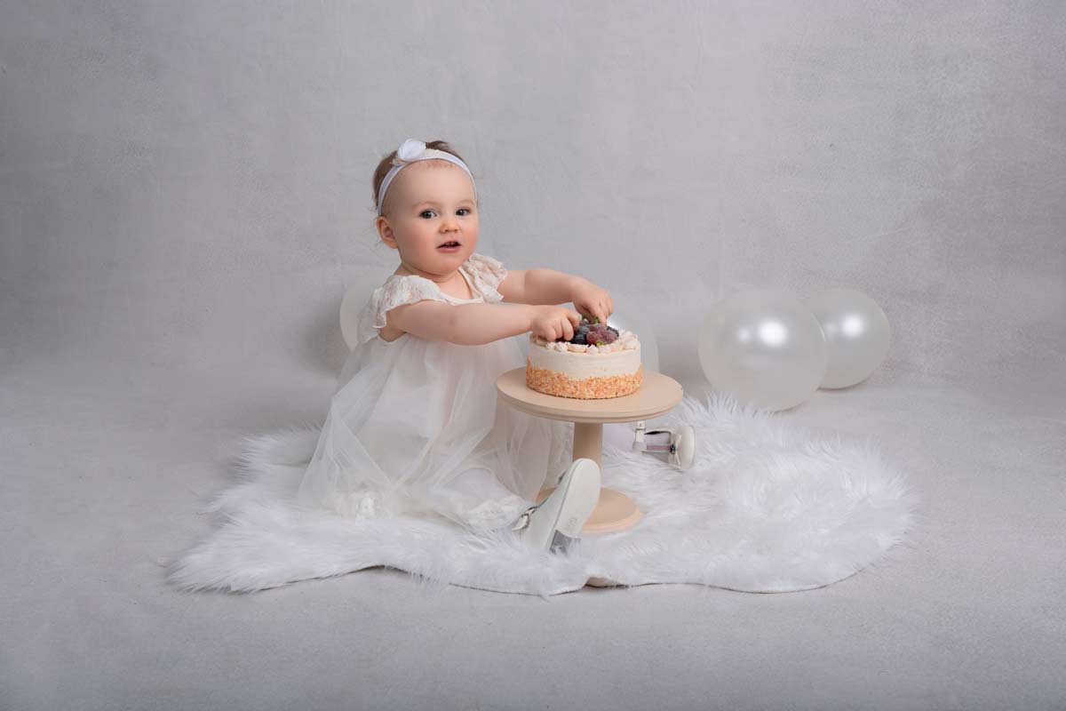 Familien-Fotoshooting-Muenchen-Nahaufnahme-der-1-jaehrigen-Geburtstagskind-in-ihrer-eleganten-weissen-Robe