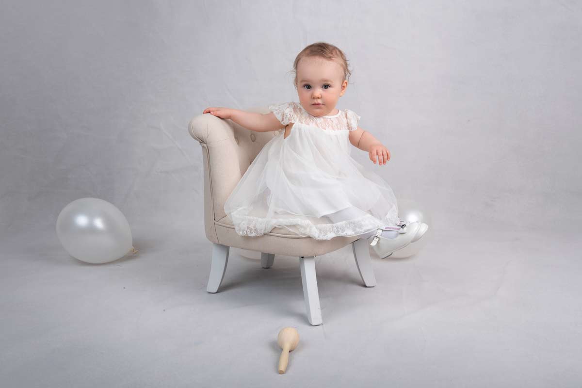 Natuerliche-Familienfotografie-Muenchen-Die-kleine-Prinzessin-lacht-herzlich-in-ihrem-Geburtstagskleid,-umgeben-von-der-liebevollen-Familie-im-Studio